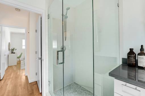 A bathroom with a glass shower door and a white cabinet.
