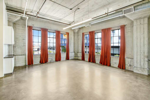 an empty room with red curtains in front of windows
