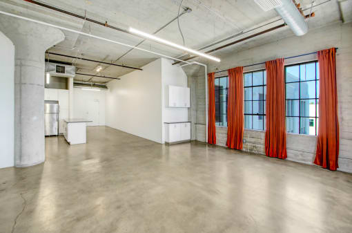 an empty room with white walls and orange curtains