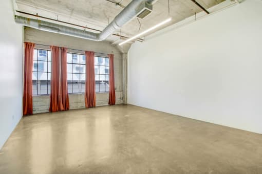 an empty room with windows and a red curtain