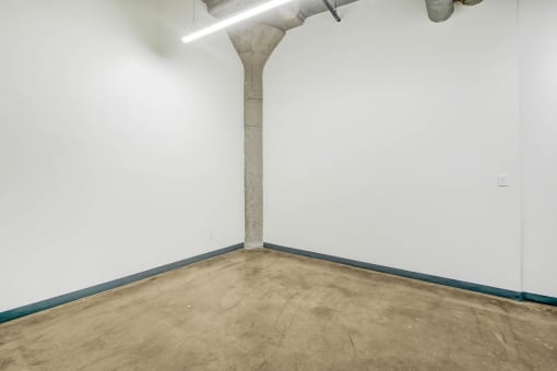 an empty room with a concrete floor and a pipe in the wall