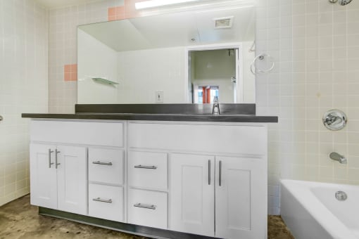 a bathroom with white cabinets and a sink and a mirror