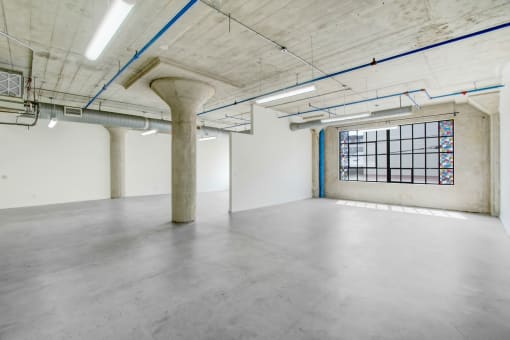 an empty room with a large window and concrete floors