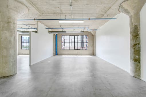 an empty room with a large window and concrete floors and walls