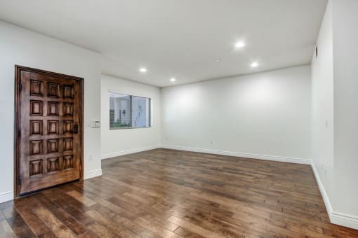 a bedroom with hardwood floors and white walls