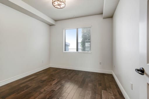 a bedroom with hardwood floors and a large window