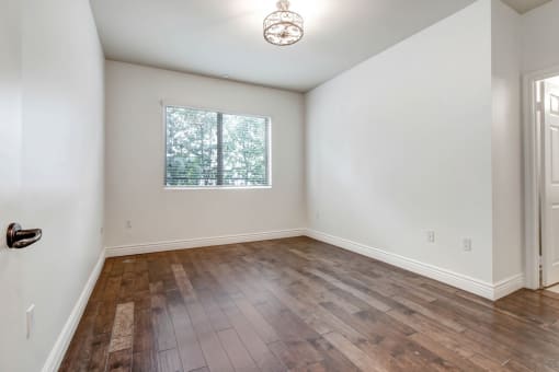 a bedroom with hardwood floors and white walls