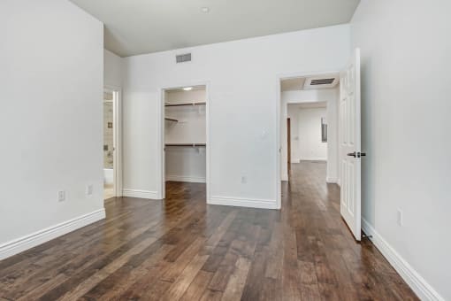a bedroom with hardwood floors and white walls