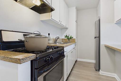 A kitchen with a black stove top and white cabinets.