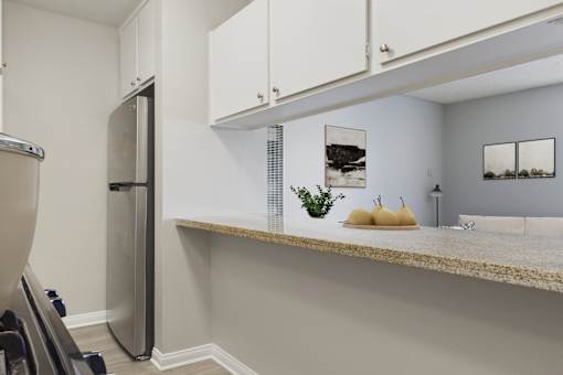 A kitchen with a stainless steel refrigerator and white cabinets.