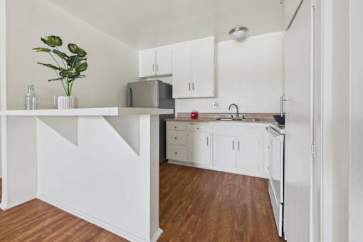 A kitchen with white cabinets and a wooden floor.