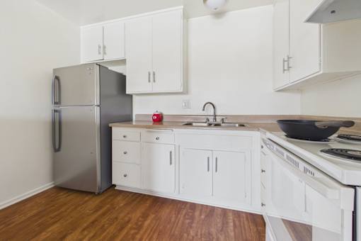 A kitchen with white cabinets and a stainless steel refrigerator.