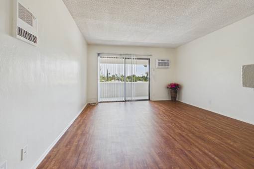 A room with a wooden floor and a sliding glass door.