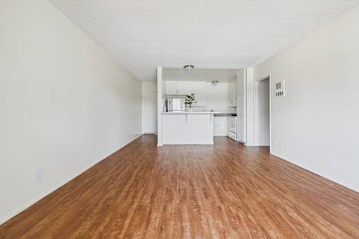A long, empty room with wooden floors and white walls.