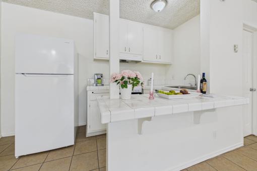 A white kitchen with a refrigerator, sink, and countertop.