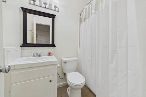 A white bathroom with a toilet, sink, and shower curtain.
