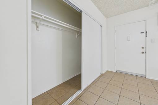 A white door is open to a room with a tiled floor.