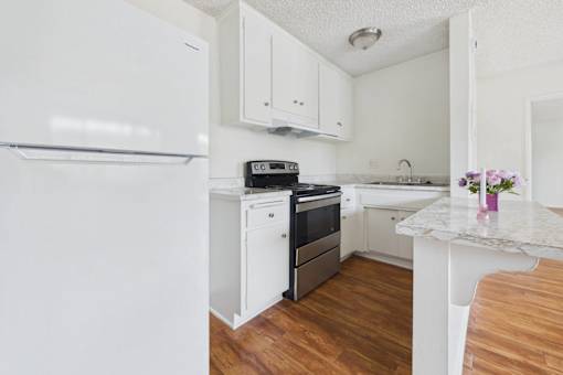 A kitchen with a white fridge, white cabinets, and a white counter.