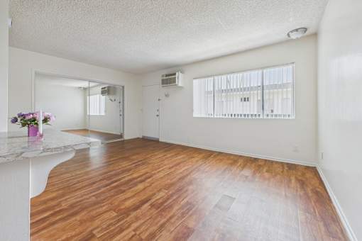 A room with wooden floors and a white countertop with flowers on it.