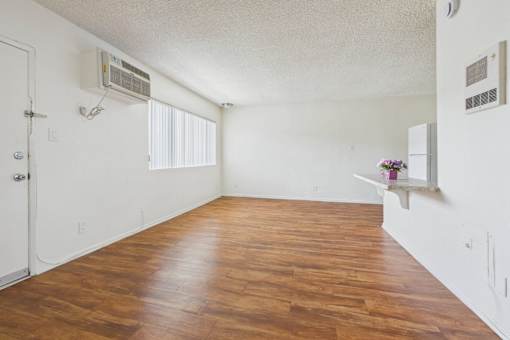 A room with wooden flooring and a window with blinds.