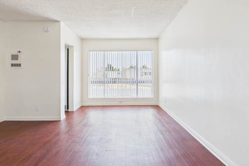 A room with a wooden floor and a window with blinds.