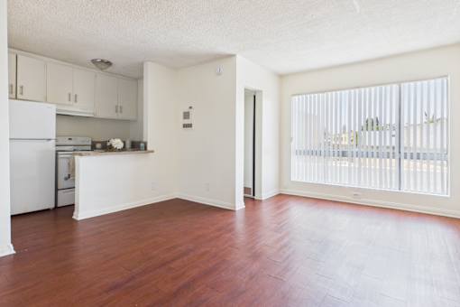A kitchen with white appliances and wooden floors.