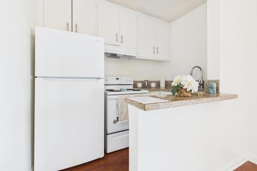 A white refrigerator stands in a kitchen with a marble countertop.