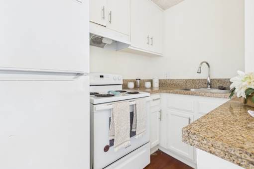 A white fridge and oven in a kitchen with a granite counter.