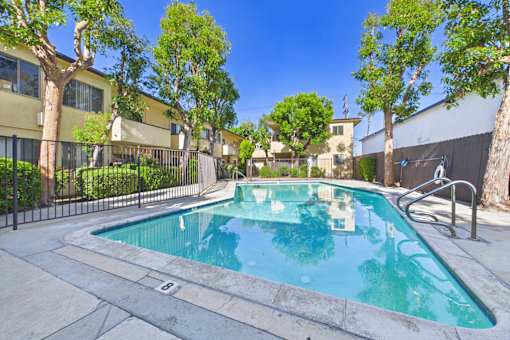 A swimming pool surrounded by trees and a fence.