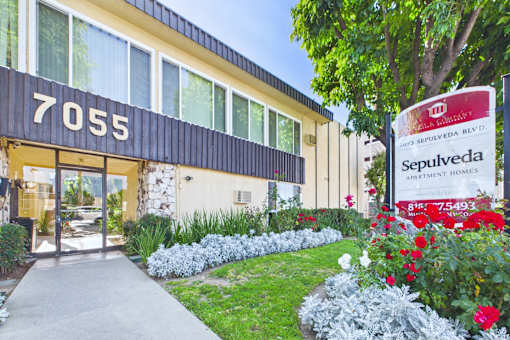 A building with the number 7055 on it and a sign for Sepulveda Apartment Homes.