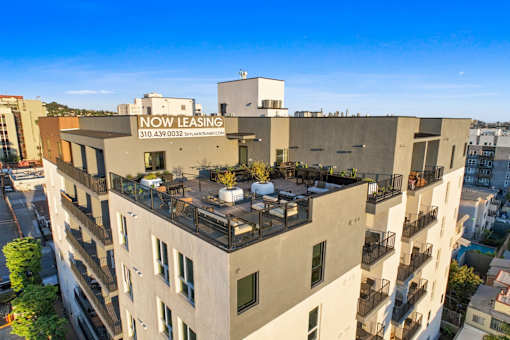 A building with a balcony and a sign that says "NOW LEASING" on top.