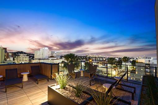 A rooftop patio with a view of the city at dusk.