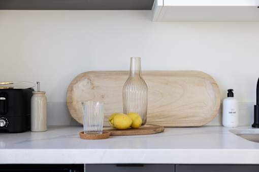 A kitchen counter with a cutting board, a bottle, a glass, and lemons at Skylar At Sunset Apartments, Los Angeles, CA