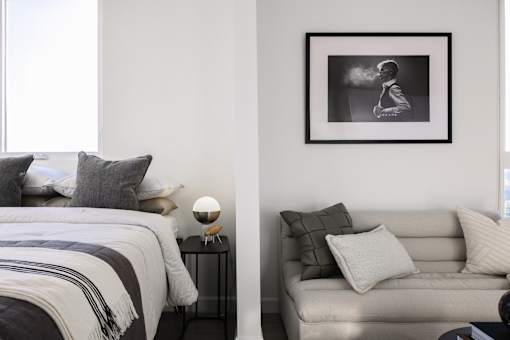 A black and white photo of a man is hanging on a wall above a grey couch at Skylar At Sunset Apartments, Los Angeles, CA, 90027