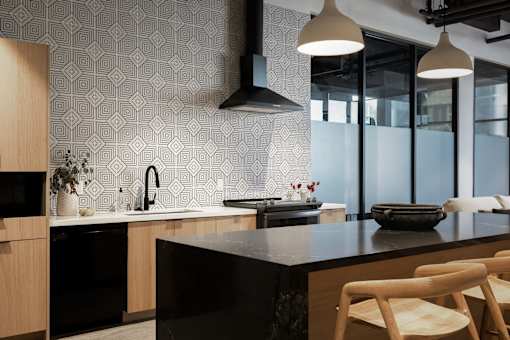 A modern kitchen with a black countertop and wooden chairs at Skylar At Sunset Apartments, Los Angeles 90027