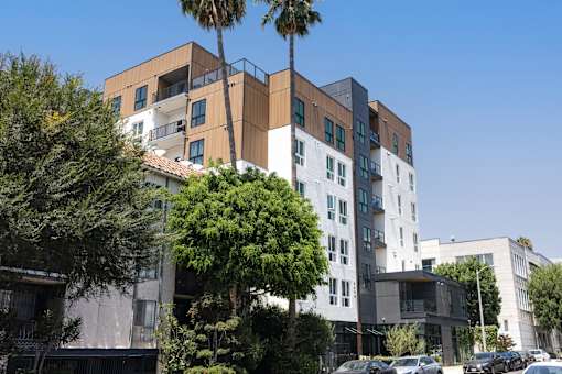 A modern building with a palm tree in front at Skylar At Sunset Apartments, Los Angeles, CA
