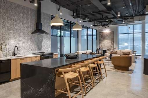 A modern kitchen with a black countertop and wooden chairs at Skylar At Sunset Apartments, Los Angeles, California