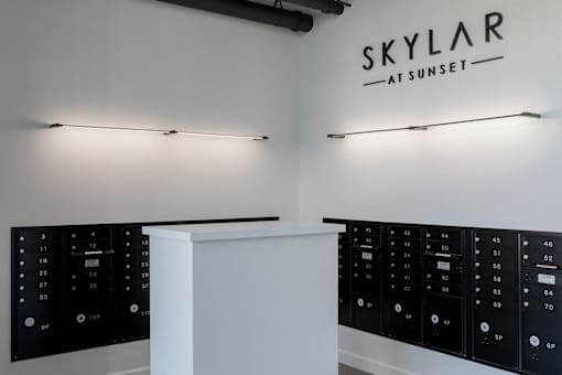 A white reception desk with a black control panel and a sign at Skylar At Sunset Apartments, California