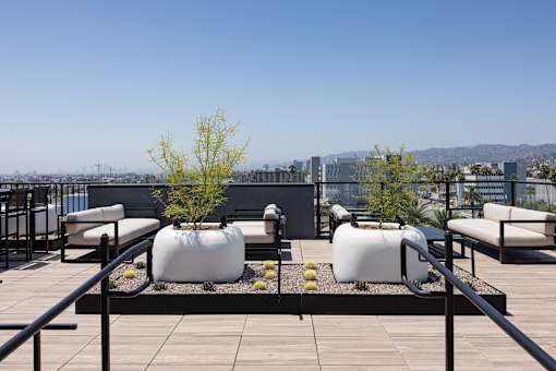 A rooftop patio with white bean bag chairs and a black railing at Skylar At Sunset Apartments, Los Angeles, CA