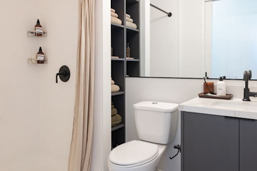 A white toilet sits next to a bathroom sink with a mirror above it at Skylar At Sunset Apartments, California, 90027