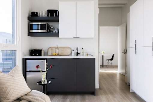 A modern kitchen with white cabinets and a black fridge at Skylar At Sunset Apartments, Los Angeles, California