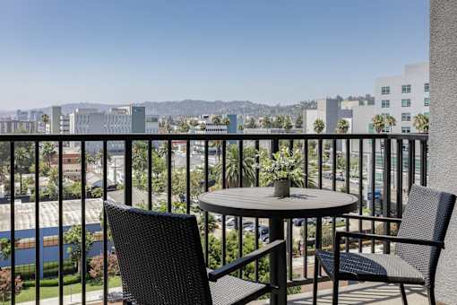 A balcony with a table and two chairs overlooking a cityscape at Skylar At Sunset Apartments, Los Angeles, CA