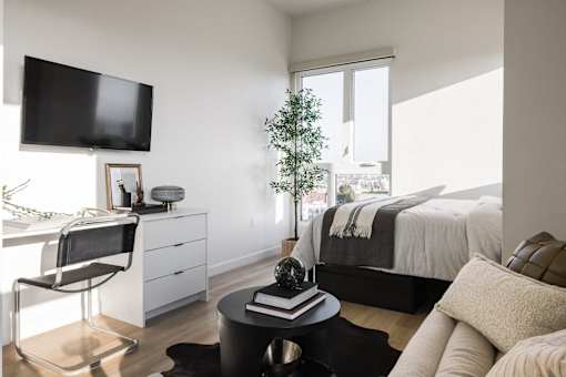 A black chair is in front of a desk with a flat screen TV above it at Skylar At Sunset Apartments, Los Angeles, CA
