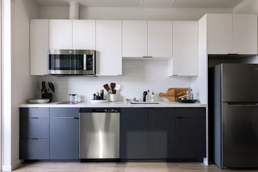 A modern kitchen with a stainless steel dishwasher and a black refrigerator at Skylar At Sunset Apartments, Los Angeles