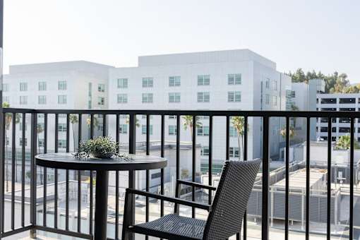 A balcony with a table and chairs overlooking a cityscape at Skylar At Sunset Apartments, Los Angeles, CA, 90027