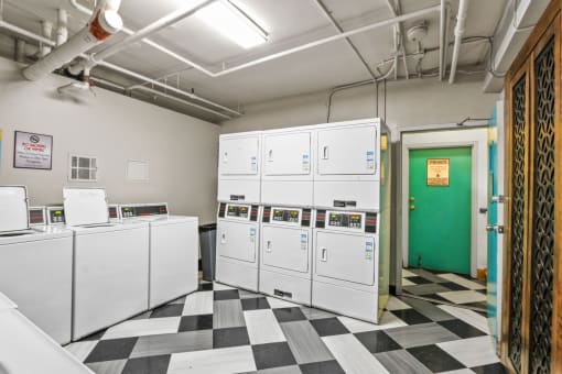 a laundry room with white machines and a green door