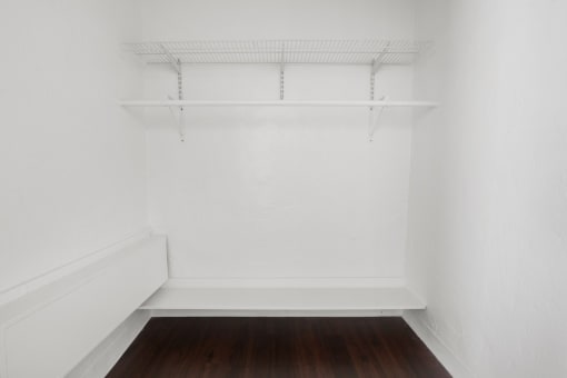 a small room with a wooden floor and a white shelf on the wall