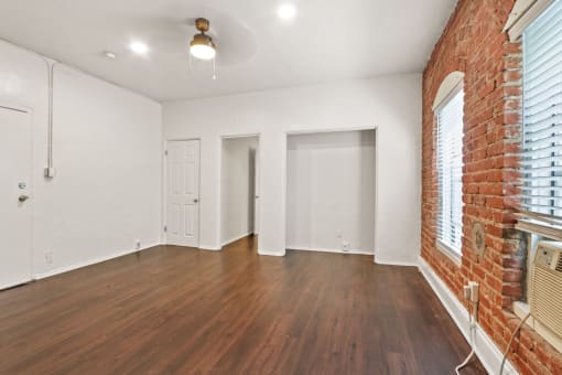 a living room with hardwood floors and a brick wall