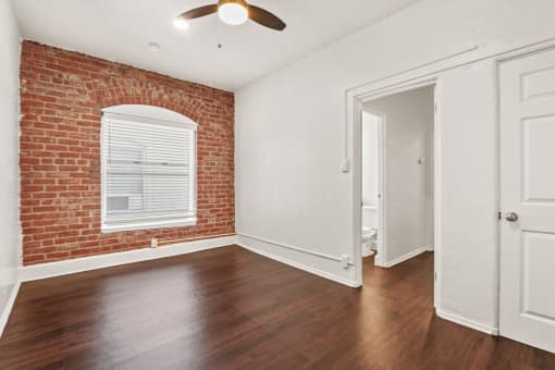 a bedroom with hardwood floors and a brick wall