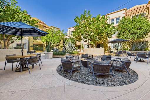 A patio with a table and chairs and umbrellas.